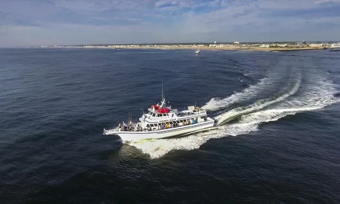 Aerial view of a party boat underway with wake and coastline